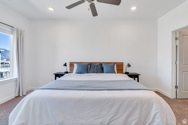 Bedroom featuring light carpet, multiple windows, baseboards, and ceiling fan | Image 8
