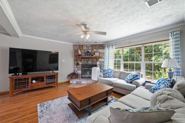 Living room featuring crown molding, a ceiling fan, wood finished floors, a textured ceiling, and baseboards | Image 8