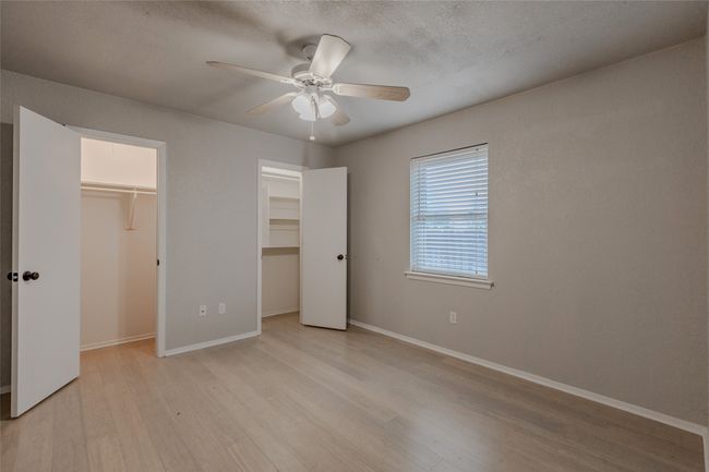 Unfurnished bedroom with light wood-style floors, ceiling fan, a walk in closet, and a textured ceiling | Image 21