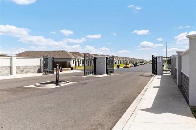 View of street featuring curbs, a residential view, street lights, a gated entry, and sidewalks | Image 29