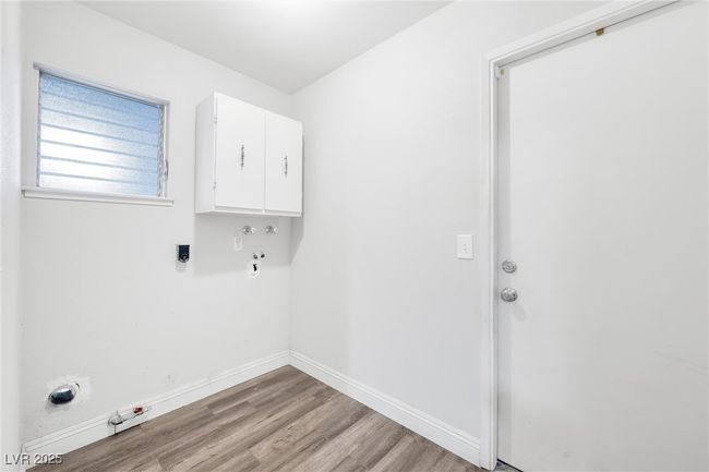 Washroom with hookup for an electric dryer, gas dryer hookup, baseboards, cabinet space, and wood finished floors | Image 15