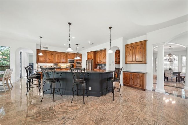Stunning, the gourmet island kitchen includes a wraparound granite surfaced and accent painted breakfast/serving bar illuminated by pendant lighting. | Image 11