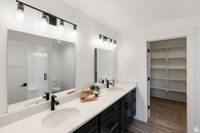 Bathroom featuring double vanity, toilet, a shower with shower door, and wood finished floors | Image 10