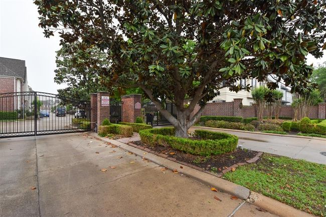 Gated community entrance featuring a wrought-iron gate, guest parking, well-maintained landscaping with mature trees in an established neighborhood | Image 31