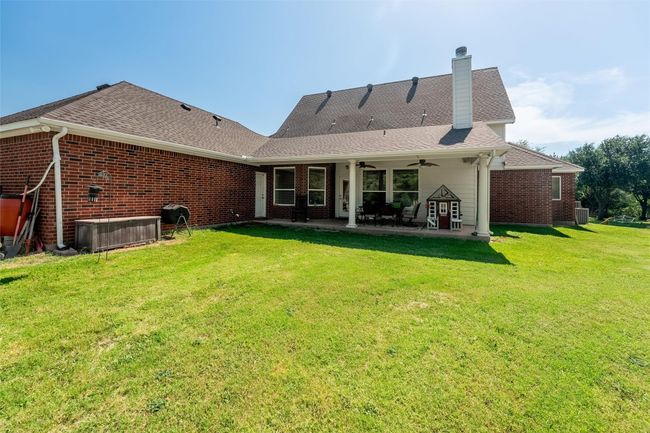 Rear view of property featuring ceiling fan, a shingled roof, and a yard | Image 18