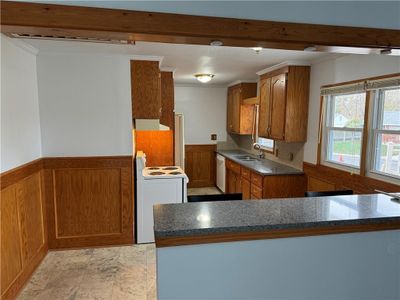 Kitchen with white appliances, sink, kitchen peninsula, range hood, and crown molding | Image 2