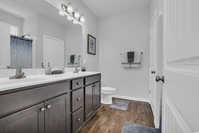 Bathroom featuring double vanity, toilet, wood finished floors, and a sink | Image 32