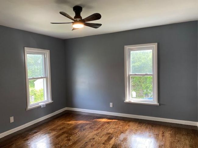 Spare room with dark wood-style flooring and a ceiling fan | Image 17