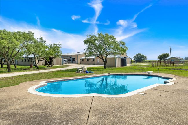 View of swimming pool with a diving board and a patio | Image 21