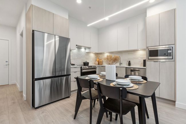 Kitchen with modern cabinets, decorative backsplash, appliances with stainless steel finishes, and light wood-style flooring | Image 7