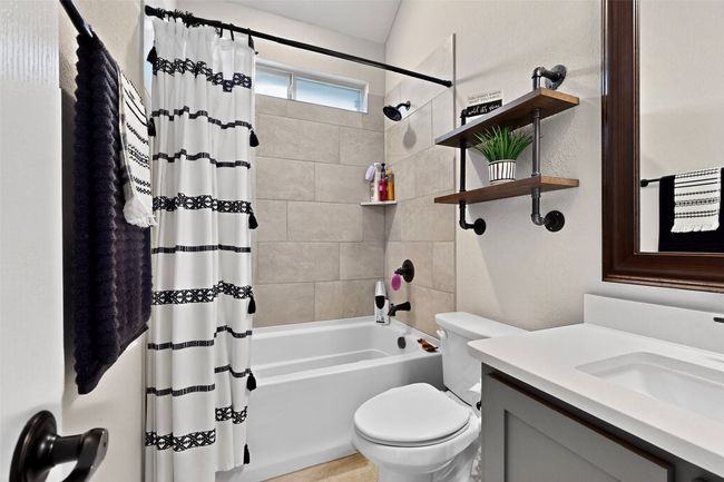 Bathroom with shower / bath combination with curtain, toilet, and vanity | Image 23