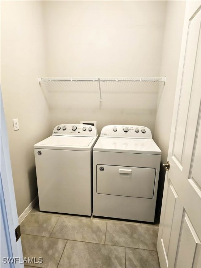 Laundry area featuring washing machine and clothes dryer, light tile patterned floors, and baseboards | Image 15