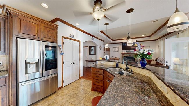 Kitchen featuring stainless steel fridge, crown molding, ceiling fan, and a sink | Image 22
