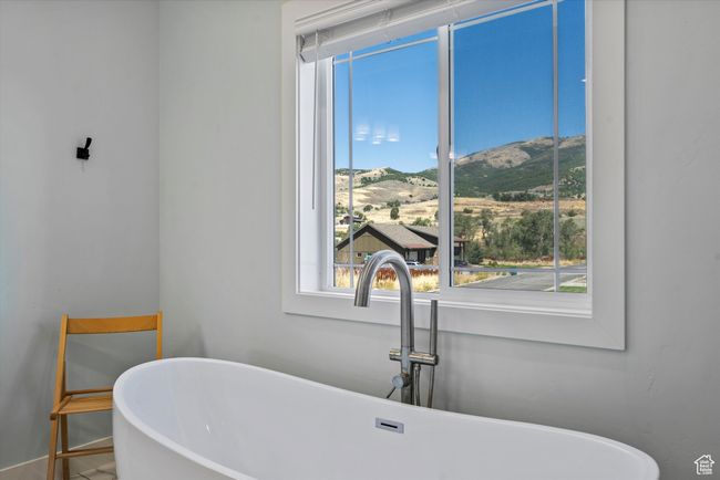 Primary full bathroom with a sink, a mountain view, a freestanding tub, and baseboards | Image 32