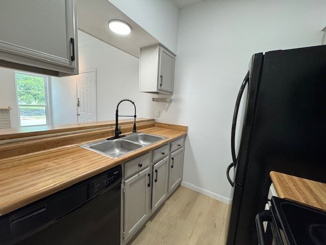 Kitchen with black appliances, light wood-style flooring, and light countertops | Image 11