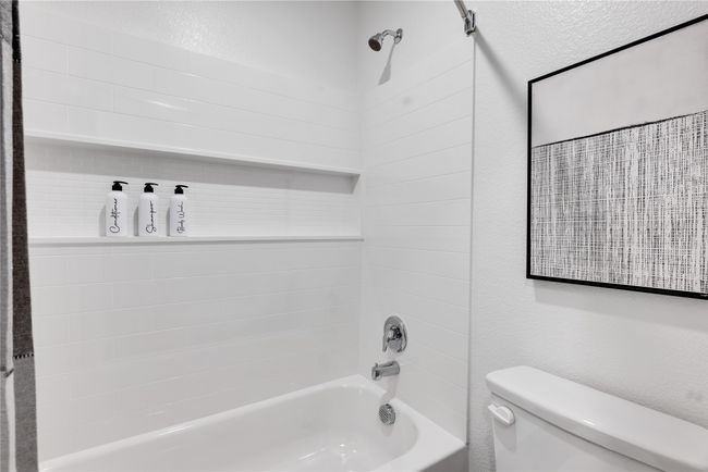 Bathroom featuring toilet, shower / bath combination, and a textured wall | Image 29