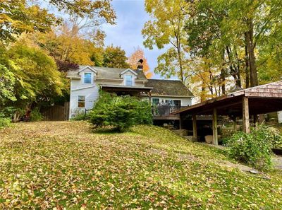 Front view of house with a wooden deck & carport Set back off the road | Image 1