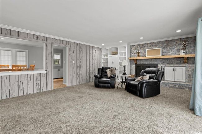 Living area with carpet floors, crown molding, recessed lighting, and a fireplace | Image 11