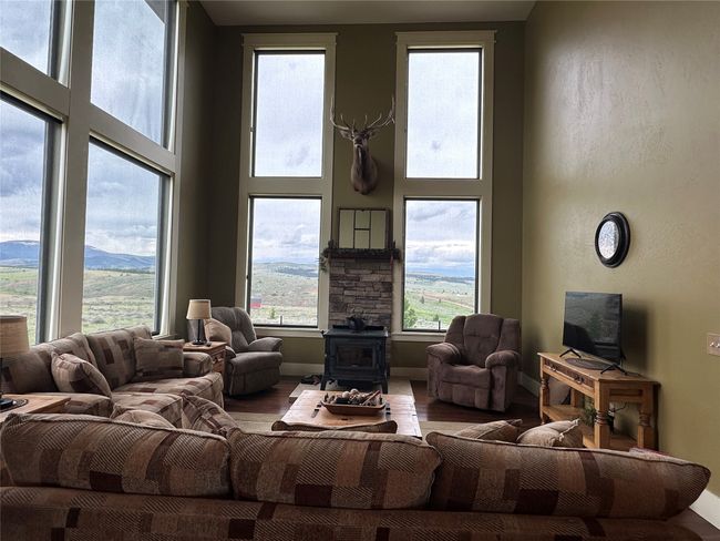 Living area with a wood stove, a high ceiling, and wood finished floors | Image 8