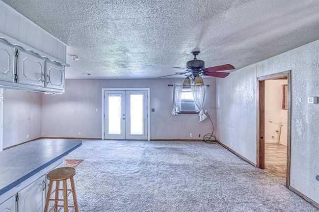 Unfurnished living room featuring light carpet, ceiling fan, a textured ceiling, french doors, and a textured wall | Image 4