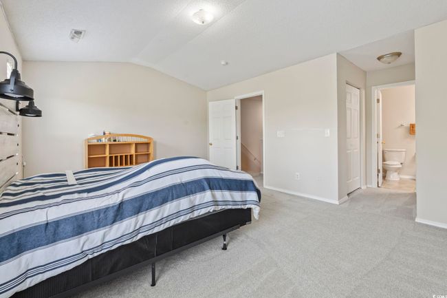 Carpeted bedroom featuring vaulted ceiling, baseboards, and connected bathroom | Image 14