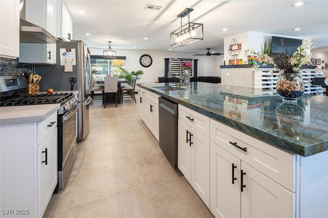 Kitchen with dishwashing machine, visible vents, stainless steel range with gas cooktop, wall chimney exhaust hood, and tasteful backsplash | Image 15