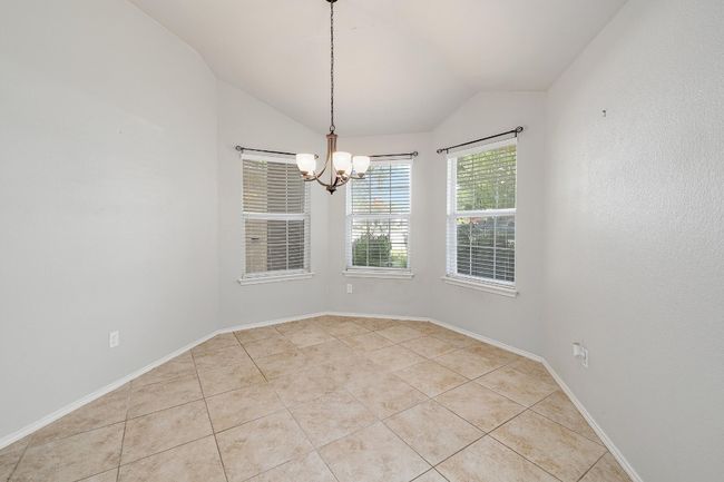 Empty room with a chandelier, vaulted ceiling, and tile patterned floors | Image 7