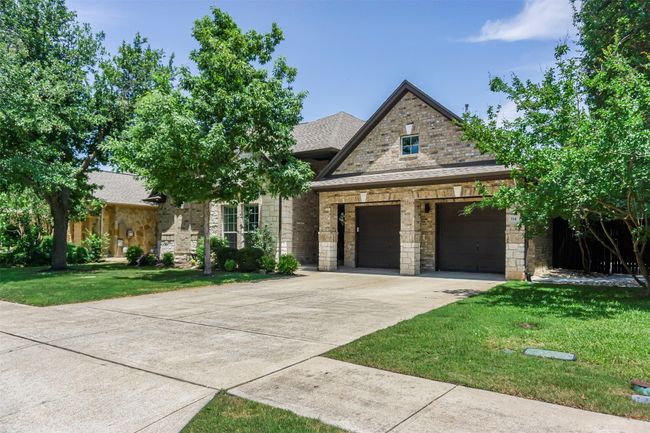 View of front of property with a front lawn, stone siding, driveway, an attached garage, and roof with shingles | Image 9