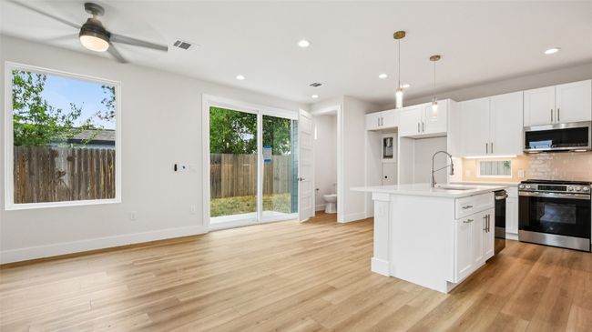 Kitchen with white cabinetry, stainless steel appliances, backsplash, recessed lighting, and hanging light fixtures | Image 13