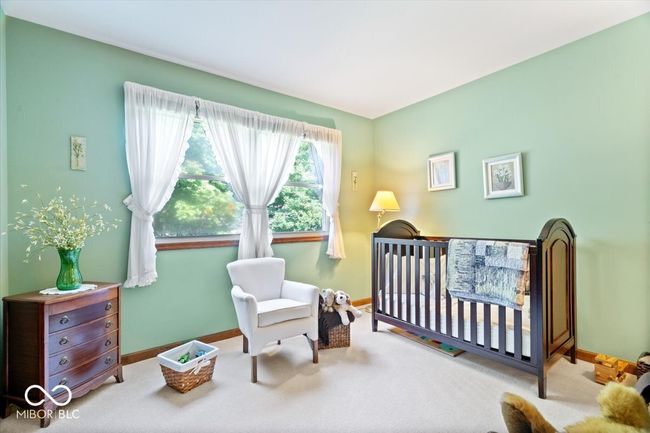 carpeted bedroom featuring a nursery area and baseboards | Image 26