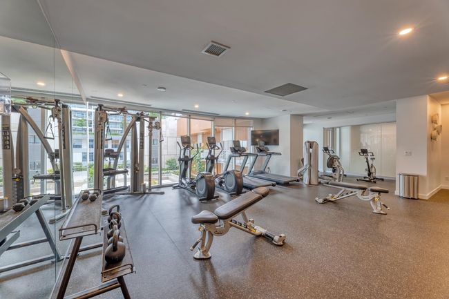 Exercise room with a wall of windows, visible vents, and baseboards | Image 18