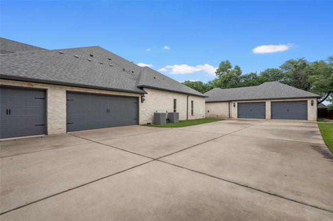 View of property exterior with a garage, central AC unit, driveway, and roof with shingles | Image 40