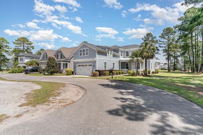 Shingle-style home with driveway, a front yard, board and batten siding, and a garage | Image 4