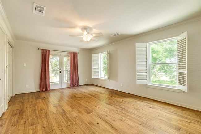 This secondary bedroom features two large windows with classic shutters and a set of French doors | Image 26