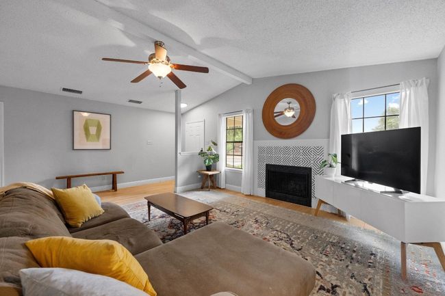 Living room with cathedral ceiling and with light engineered wood flooring, ceiling fan, a tiled wood-burning fireplace. | Image 5