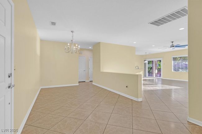 Dining area next to living room featuring light tile patterned floors, recessed lighting, baseboards, and ceiling fan with notable chandelier | Image 6