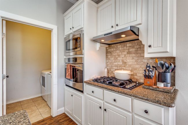 The kitchen has been thoughtfully updated with granite countertops, classic beadboard cabinetry, a large center island with built-in sink, and stainless steel appliances—including gas cooktop, built-in oven and microwave. | Image 11