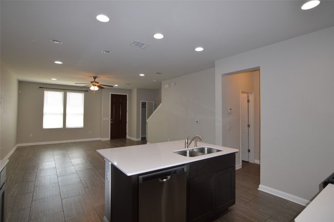 Kitchen featuring dishwasher, a sink, light countertops, a ceiling fan, and an island with sink | Image 8