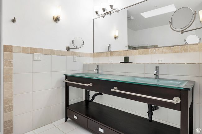 Full bathroom featuring tile patterned floors, a wainscoted wall, a sink, tile walls, and a skylight | Image 14