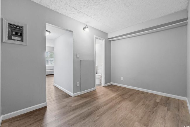 Empty room with wood finished floors, a textured ceiling, and baseboards | Image 5