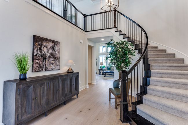 Stairs featuring wood finished floors, a towering ceiling, and a chandelier | Image 5