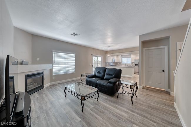 Living room featuring a textured ceiling, light wood finished floors, and a tile fireplace | Image 7