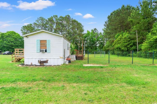 View of yard featuring a deck, cooling unit, and view of scattered trees | Image 20