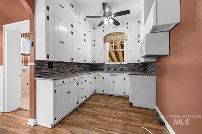 Kitchen with a ceiling fan, white microwave, wood finished floors, and tasteful backsplash | Image 14