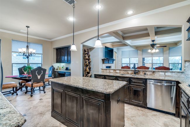 The kitchen flows into the spacious breakfast area. This area has a doorway to the side yard. There is also a workstation with built-in cabinets and undermount lighting. The entire kitchen and breakfast areas are trimmed with crown molding. | Image 17