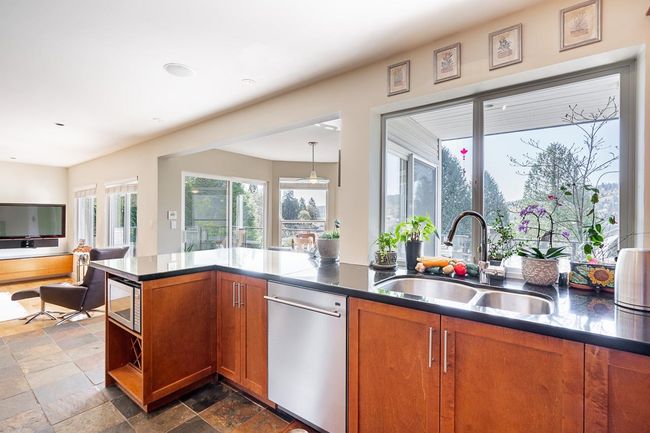 Kitchen featuring stainless steel appliances, brown cabinetry, stone tile floors, and dark countertops | Image 11