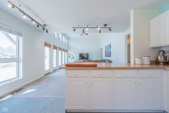 kitchen with a peninsula, light countertops, open floor plan, white cabinetry, and track lighting | Image 10