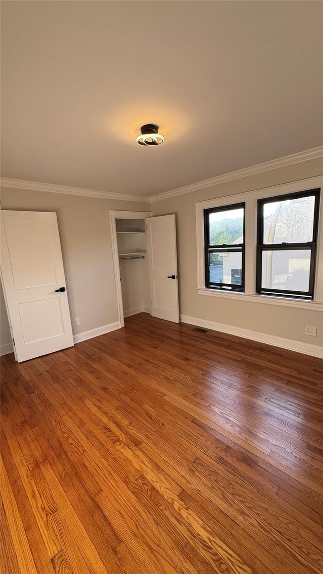 Unfurnished bedroom with wood finished floors, a closet, and ornamental molding | Image 18
