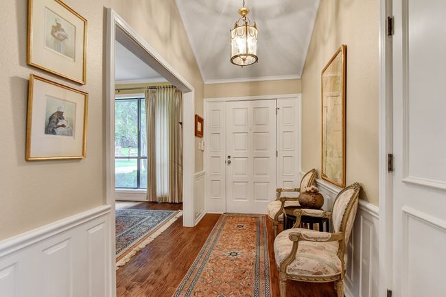 Entryway featuring dark wood-style flooring, wainscoting, a chandelier, a decorative wall, and ornamental molding | Image 5