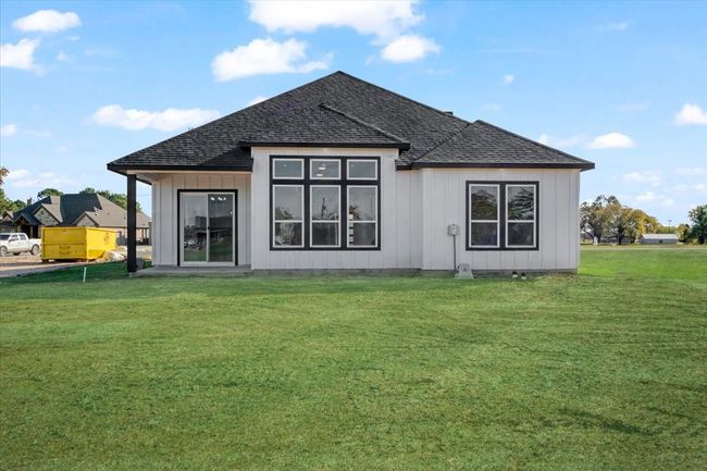 Back of house featuring a shingled roof, a lawn, and board and batten siding | Image 24